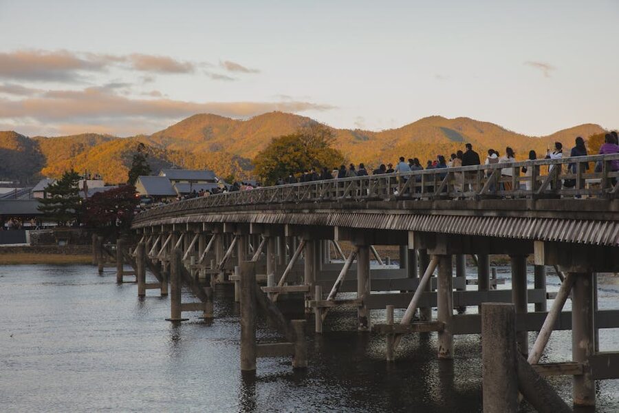 Travellers crossing the wooden Togetsukyo Bridge over the Hozu river in Arashiyama, Kyoto
