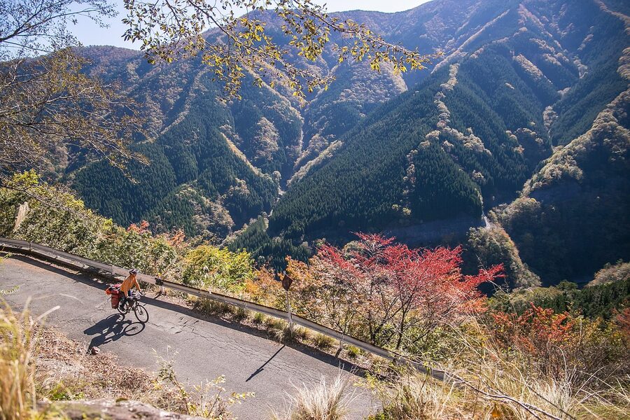 A cyclist on a road heading into mountains