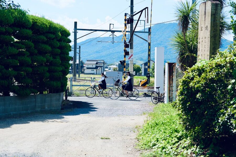 Two cyclists waiting at a railway crossing in rural Japan